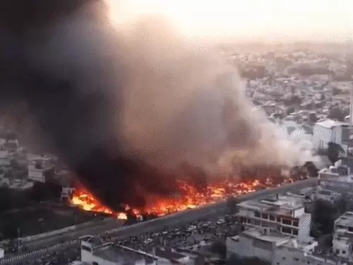 लखनऊ विकास नगर में लगी भीषण आग में झुग्गियां जलती हुई और धुआं उठता हुआ दृश्य