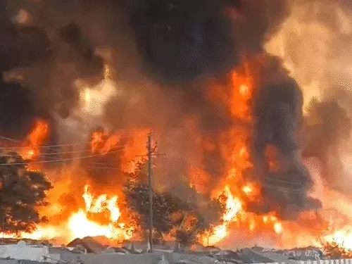 लखनऊ के विकासनगर इलाके में भीषण आग के बाद जली हुई झुग्गी-झोपड़ियां, दमकल की गाड़ियां आग बुझाते हुए और धुएं के बीच बचाव कार्य करते लोग।